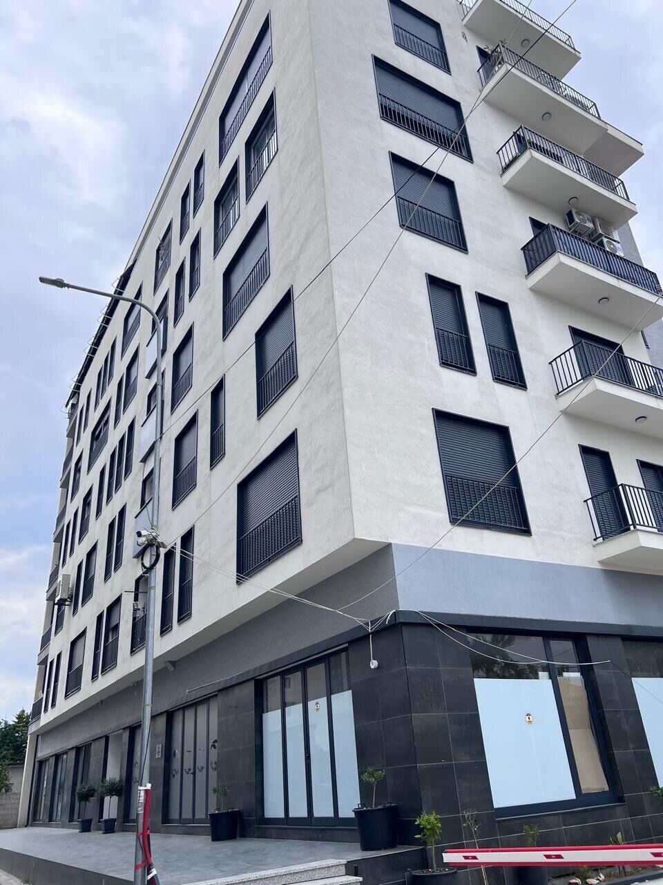 A multi-story building with a modern architectural design, featuring balconies on the upper floors and large windows on the lower levels.