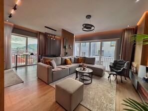 A modern living room with a sectional sofa, a round coffee table, and a black armchair. - Luxury Apartment Shkoder (shkoder)