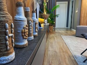 Eine Reihe dekorativer Vasen auf einem Regal, ein Holzboden und eine Pflanze im Hintergrund.