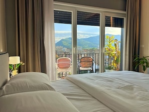 Ein Hotelzimmer mit einem großen Bett, einem Balkon mit Stühlen und Bergblick.