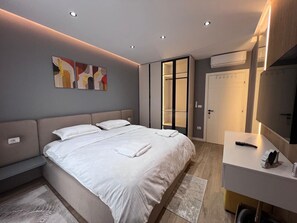 A modern hotel room with a large bed, bedside tables, a desk, and a television. - Luxury Apartment Shkoder (shkoder)