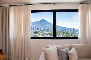 A room with a large window, a sofa, and curtains.