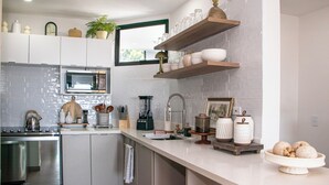 A modern kitchen with white cabinetry, a built-in microwave, and a coffee machine.