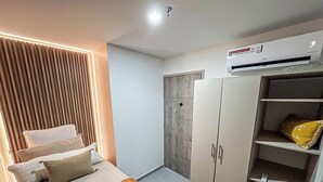 A bedroom with a bed, a wardrobe, and an air conditioning unit.