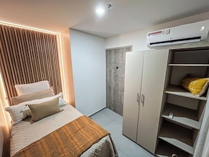 A bedroom with a bed, a wardrobe, and an air conditioning unit.