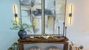 A wooden console table with a potted plant, decorative items, and wall-mounted lights.