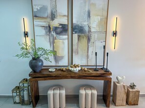 A wooden console table with a potted plant, decorative items, and wall-mounted lights.