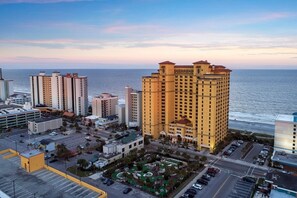 A high-rise hotel with multiple floors, a parking area, and a view of the ocean. - Myrtle Beach | Family Oceanfront Getaway | Pool + Beach | 3BR Sleeps 8 (Myrtle Beach)