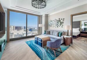 Ein modernes Hotelzimmer mit weitreichendem Stadtblick, einer Couch, einem Sessel, einem Nachttisch und einer Lampe.