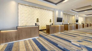 A hotel reception area with a patterned wall, multiple reception desks, and a carpeted floor. - Las Vegas | Pool & Strip Access | 2BR Plus (Las Vegas)