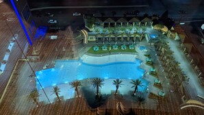A pool area with a curved design, palm trees, and lounge chairs. - Las Vegas | Pool & Strip Access | 2BR Plus (Las Vegas)