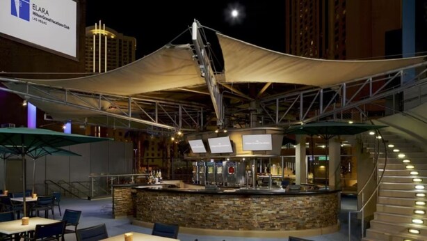 An outdoor bar area with a stone counter, outdoor seating, and a large canopy. - Las Vegas | Pool & Strip Access | 2BR Plus (Las Vegas)