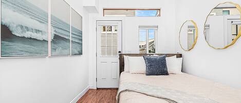 Un dormitorio con cama, armario, ventana y espejo.