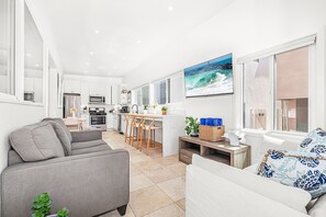A modern kitchen with white cabinets, a microwave, and a large window. - Charming 5BR Group Bungalow Steps to Sand with Deck and Fire Pit (Newport Beach)