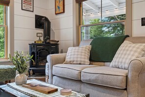 Una sala de estar acogedora con chimenea, un sofá y vistas al exterior.