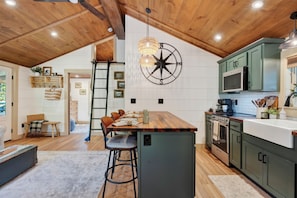 Una cocina moderna con una isla central, techo de madera y armarios verdes.