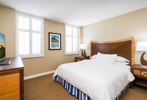 Una habitación de hotel con una cama, un escritorio, una lámpara y un cuadro en la pared.
