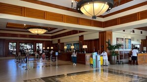 A hotel lobby with a reception desk, a large chandelier, and a check-in counter. - Waikiki | Resort Lagoon Stay | Pools & Beach Access (Honolulu)