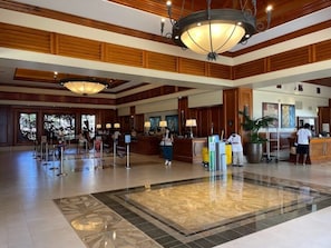 Un vestíbulo de hotel con una recepción, una lámpara de araña grande y un mostrador de registro.