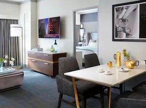 Hotellihuone, jossa on sänky, työpöytä tuolilla, televisio ja seinällä oleva kehystetty kuva.