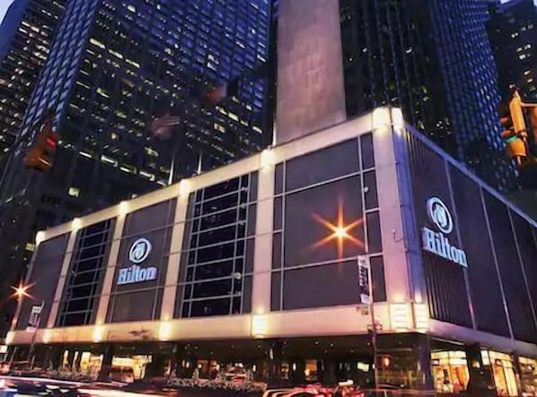 Hilton-hotelli, jossa on moderni julkisivu, suuret ikkunat ja huomiota herättävä, korkea pylväs.