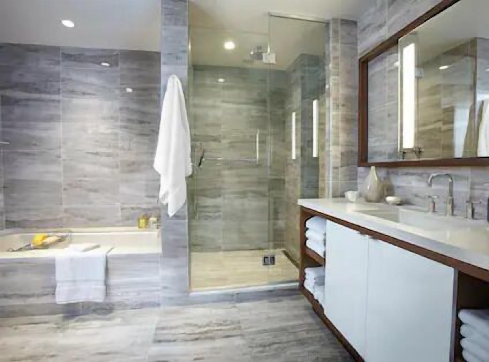 Un baño moderno con ducha de vidrio, bañera y tocador con espejo.