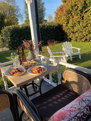 Ein Essbereich im Freien mit einem Tisch für zwei Personen, komplett mit Pasta, Brot, Weingläsern und einer Weinflasche.