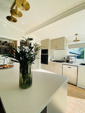 A modern kitchen with a central island, stainless steel appliances, and a large window.