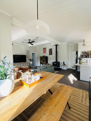 A spacious living area with a wooden dining table, a sofa, and a television.