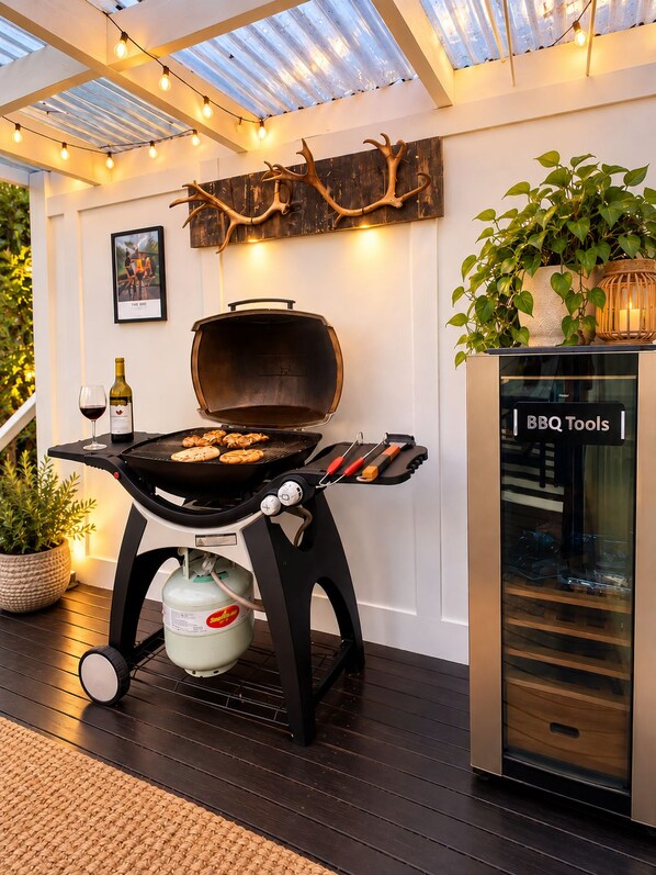 A barbecue grill with a gas tank, a glass cabinet with tools, and a potted plant.