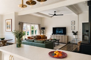 A modern living room with a sofa, television, and a dining area with a table and chairs.