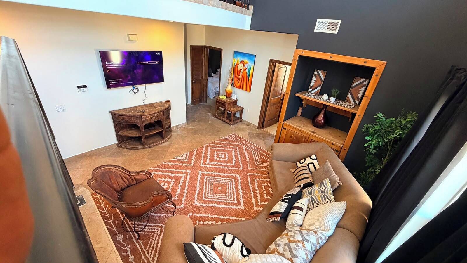 Ein Wohnzimmer mit Fernseher, einer Couch, einem gemusterten Teppich und einer Holzkommode.