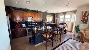A modern kitchen with dark wooden cabinets, stainless steel appliances, and a central island with bar stools.