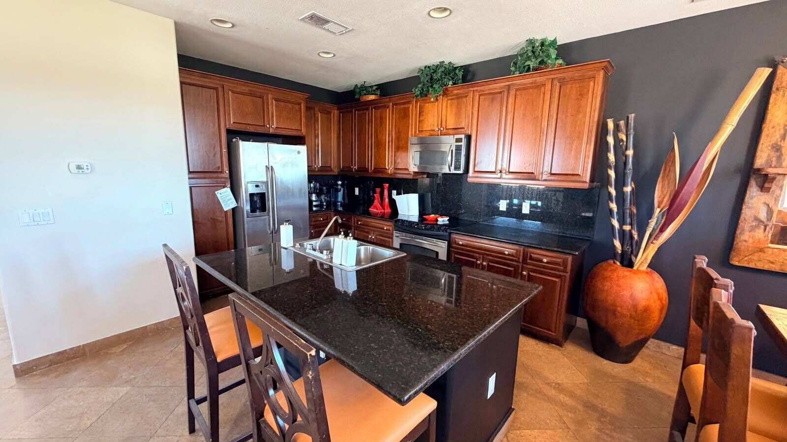 Una cocina moderna con armarios de madera, encimera de granito y microondas integrado.