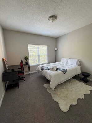 A bedroom with a bed, a desk, a chair, a window with blinds, and a ceiling light. - Home away from home (Atlanta)