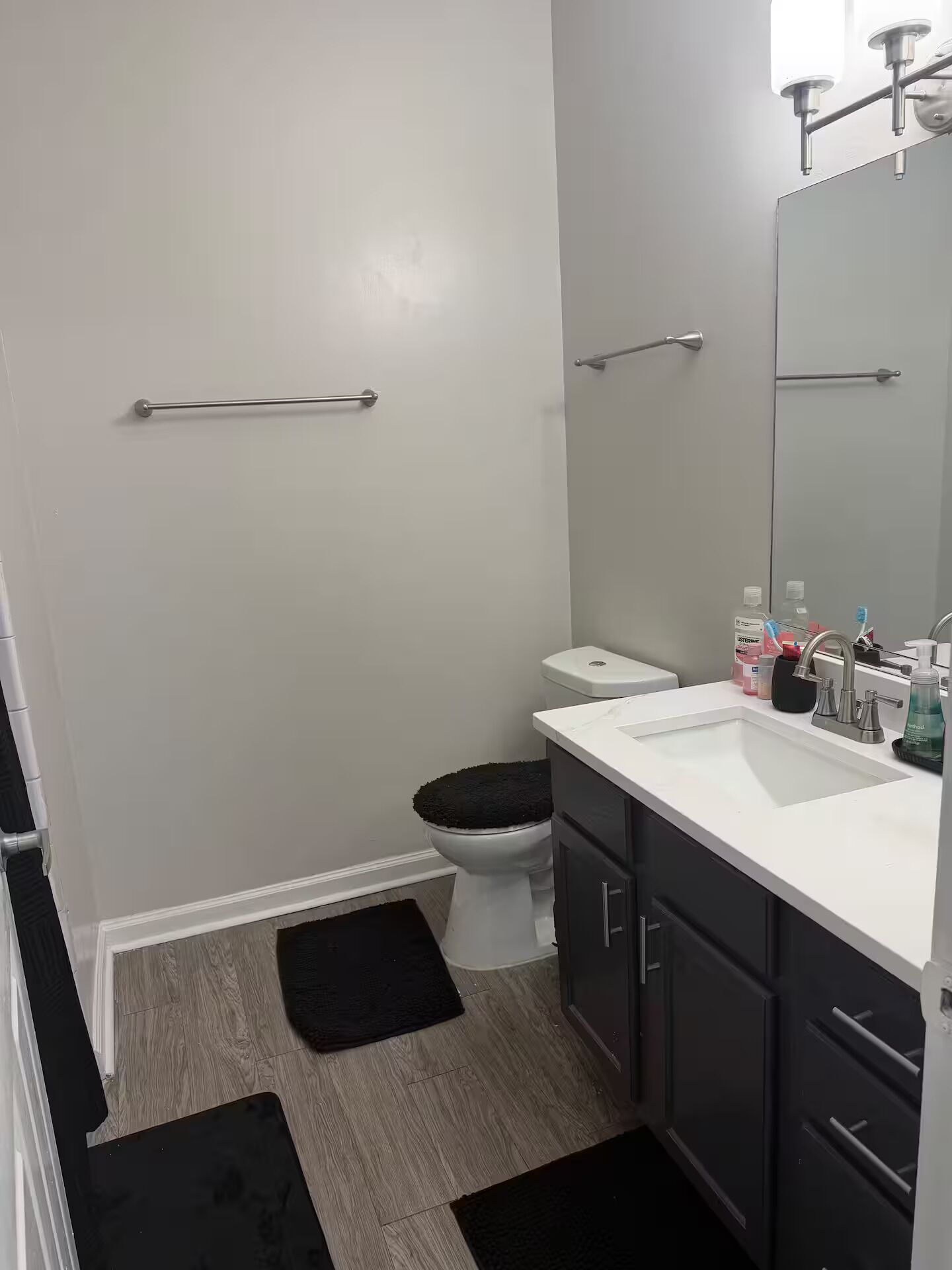 Een badkamer met toilet, wastafel, spiegel en een handgreep.