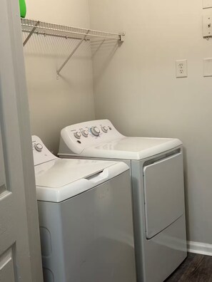 A laundry area with two front-loading washing machines and a drying rack. - Home away from home (Atlanta)