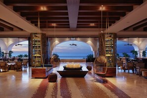 A spacious lobby with a view of the ocean, a bar area, and seating arrangements. - Los Cabos | Elevated Coastal Stay | Pool + Beach (Los Cabos)