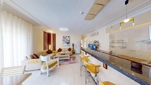 A modern living room with a sofa, coffee table, and a dining area with bar stools. - Enjoyable Home Away Stay (Amman)