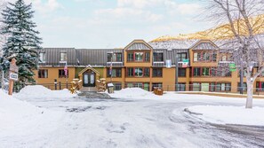 A lodge with a central entrance, multiple windows, and a snow-covered ground. - Vail | Alpine Getaway | Pool & Hot Tub | 2BR (Vail)