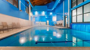 An indoor swimming pool with clear water, surrounded by blue walls and wooden ceiling beams. - Vail | Alpine Getaway | Pool & Hot Tub | 2BR (Vail)