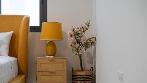 A bedroom with a bed, a nightstand with a lamp, and a potted plant. - SOL Euphoria Walk to Beach Town (Ocho Rios)