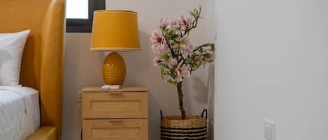 Une chambre à coucher avec un lit, une table de chevet avec une lampe et une plante en pot.