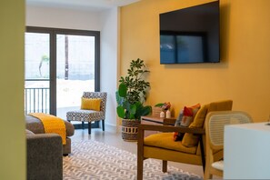 A modern living room with a sofa, armchair, and a large potted plant. - SOL Euphoria Walk to Beach Town (Ocho Rios)