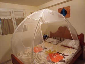 Een bed met hemelbed, een houten hoofdbord en bloemenbedrukte beddengoed.