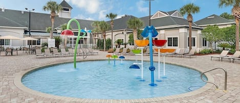 A swimming pool with colorful water features and lounge chairs.