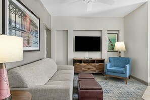 Una sala de estar moderna con un sofá, un sillón azul, un televisor de pantalla plana y una mesa de centro.
