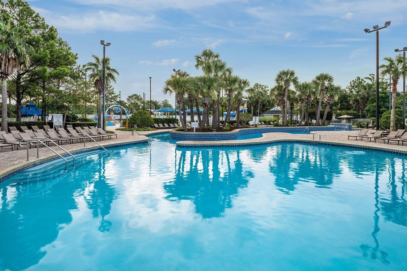 Una piscina con tumbonas y palmeras.