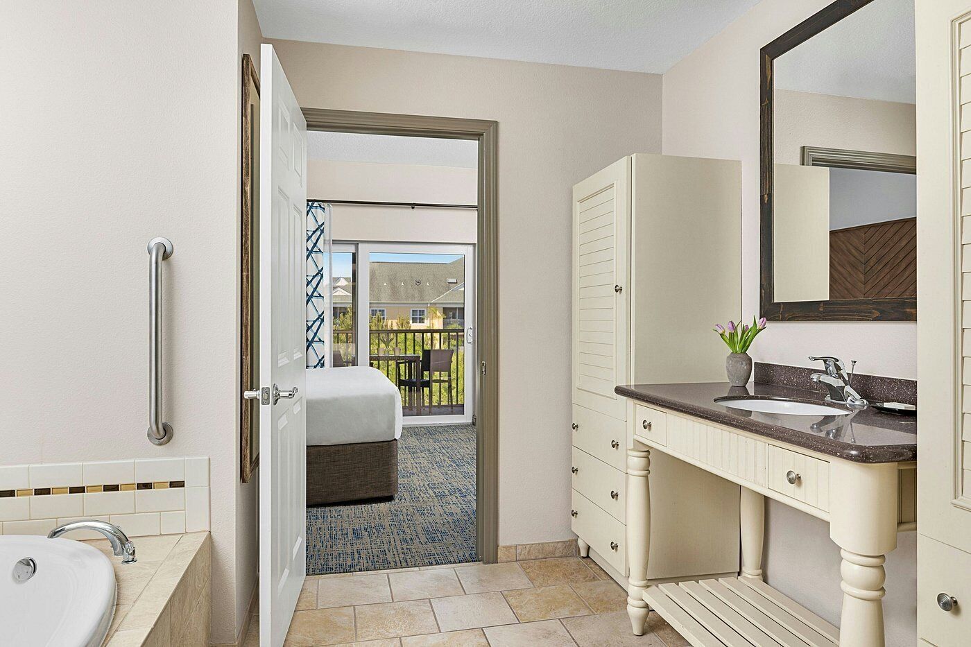 Ein Badezimmer mit Badewanne, Waschbecken, Spiegel und einer Tür, die auf einen Balkon führt.