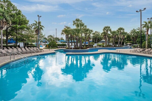 A swimming pool with lounge chairs and palm trees. - Myrtle Beach | Group Beach Retreat | Pool + Hot Tub | 2BR (Myrtle Beach)